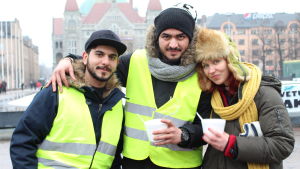 Pastor Marjaana Toiviainen är med och ger demonstrationen sitt stöd tre personer i vinterkläder med nationalteatern i Hfrs i bakgrunden