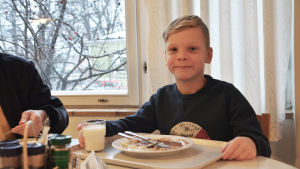 Lite äldre och yngre barn har kommit med sina föräldrar till Strömborgska skolan. Skollunchen smakar gott för det unga barnet