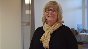 Benita Öberg började jobba som social- och hälsovårdsdirektör i Raseborg i början av augusti 2018. Före det har hon jobbat med motsvarande uppgifter i bland annat Sjundeå, Lojo och Ingå. En kvinna utanför sitt tjänsterum, tittar in i kameran och ler