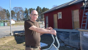 Henrik Huldin är byarådets ordförande i Bromarv. En man med skottkärra vid ett bygge. Bakom ett halvfärdig byggnad med väggar målade i rödmylla.