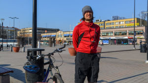 Matti Kummu fraktar plast till närmaste återvinningspunkt med cykel. Matti Kummu ute på ett torg.