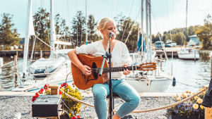 Trots att Tove Ljungqvist känner sig finlandssvensk framför hon sina låtar på rikssvenska. Tove Ljungqvist uppträder vid en hamn.