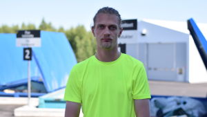 Kristian Lagerroos berättar att han själv lärt sig mycket om avfallssortering genom sitt arbete på företaget. En ung man i gul arbetsskjorta som står framför avfallssorteringskärl.