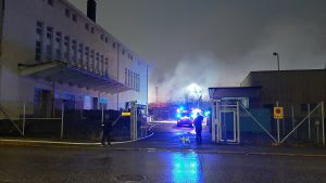 Det värsta av branden är släckt. Nu är röken det största problemet. Byggnad brinner. Räddningspersonal i bakgrunden.