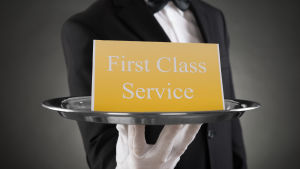 Servitör håller fram en silverbricka med texten "First Class Service".