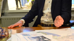 Jan D. Oker-Blom har fullt upp och pappren samlas på bordet Jan D. Oker-Bloms händer