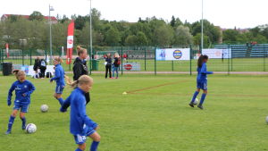 Laget som Malaska tränar tycker att det är viktigt att vinna, men ser även vikten av att njuta och ha roligt. Fotbollstränaren Sanna Malaska, klädd i svart, ser på då hennes juniorlag värmer upp, klädda i blått.