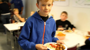 Ett varmt mål mat om dagen är viktigt, ibland är det det enda som barnet får under dagen. Pojken på bilden har ingenting att göra med innehållet i texten. Köttbullar till skolmat.