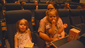 Mamma Helena Granqvist och Melissa och Melanie Lindell En mamma och två flickor sitter i en biosalong
