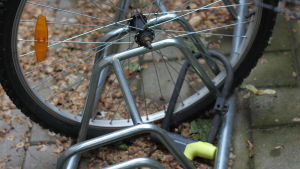 Ett ordentligt fastlåst hjul hjälper inte om någon skruvar loss ramen. Ett cykelhjul som är fastlåst i en cykelställning. Någon har stulit själva cykeln.