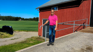 Markus Johansson har inte ännu tänkt så mycket på vad han ska göra då dottern tar över gården. En man står framför en åker och en röd träbyggnad.