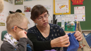 Läraren Peggy Wallin använder stödtecken också när kom kommunicerar utanför skolan. Lärare hjälper elev att sy.