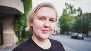 Aino Koivisto katsoo suoraan kameraan. Taustalla vihertävä Jyväskylän katukuva.