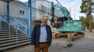 Tomas Kurtén var glad när ishallsrenoveringen kom igång. Nu kan man öppna för hemmapubliken med nyrenoverade utrymmen. Tomas Kurtén, vd för Vasa Sport, står leendes intill ishallen i Vasa som renoveras. En grävmaskin syns i bakgrunden.