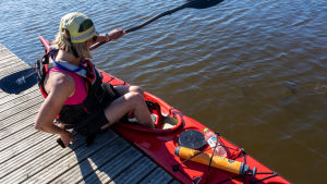 För en nybörjare är påstigningen en lite intressant utmaning. Charlotta Bengs på bryggan på väg in i sin röda kajak.