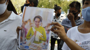 Demonstranter visar upp bilder av den fängslade Aung San Suu Kyi under en protest utanför FN:s högkvarter i Bangkok i Thailand. Demonstranter visar upp bilder av den fängslade Aung San Suu Kyi under en protest utanför FN:s högkvarter i Bangkok i Thailand.
