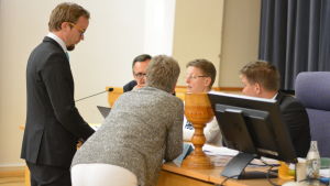 En stund uppstod förvirring under mötet då ersättaren Mikael Borgman fattades. Det blev paus och överläggelser. Men efter att kloka huvuden slagits ihop ansågs mötet vara lagligt sammankallat och beslutfört Palaver med flera ledamöter runt ordföranden under fullmäktigemöte.