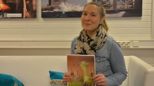 Tove Gestranius med en råkopia på den nya kursbroschyren. Kvinna håller i en broschyr.