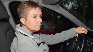 Annette Ström är bekymrad och besviken över stadens sätt att sköta skoltransporter i glesbygden. En kvinna sitter bakom ratten i en personbil. Mörkt ute. Hon ser fundersam ut.