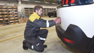 Alexander Laurila fäster registerskylten på bilen. Laurila har jobbat åtta månader på SE Mäkinen i Hangö. Han lärde sig PDI-granskningen på jobbet. Alexander Laurila sätter fast registerskylten på en bil.