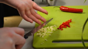 Skärbräde med vitlök och chili Skärbräde med uppskuren vitlök och chilifrukt.