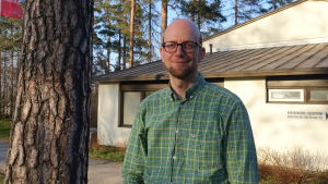 Panu Pihkala är miljöforskare vid Helsingfors universitet. man i grön skjorta invid trädstam