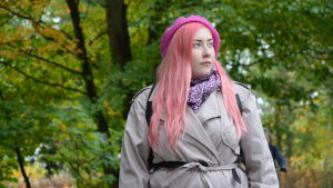 Rosanna Fellman blev positivt överraskad då hon fick veta att hon beviljats ett ettårigt arbetsstipendium. en kvinna i rosa hår och grå jacka står bland grönskande träd