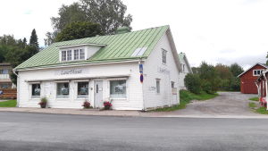 Laserhuset kommer att säljas, likaså småhuset som skymtar bakom. Arkivbild från augusti 2020. En vit träbyggnad med grönt tak i Ingå kyrkby som kallas laserhuset.