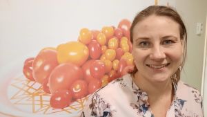 Ska vi lyckas locka arbetstagare från längre bort, måste vi hela tiden visa att vi är attraktiva som arbetsgivare, säger Paola Bodbacka. En kvinna tittar leende in i kameran intill en tavla full med tomater.