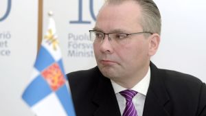 Jussi Niinistö Porträtt på försvarsminister Jussi Niinistö vid en standard med finska flaggan.