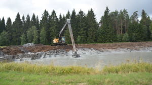 De här grävmaskinerna har långa armar som effektivt klarar av att flytta stora mängder lera och... En grävmaskin gräver en sedimenteringsbassäng på en åker. Blivande våtmark