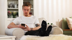 Iilahtis skärmtid sköt i höjden under de svåra åren. Jonathan Iilahti sitter i en stol och ser på telefonen.