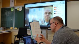 Klasslärare Jörgen Holmberg visar en sida i matematikboken för en elev via datorns kamera. Lärare Jörgen Holmberg distansundervisar 20.03.20