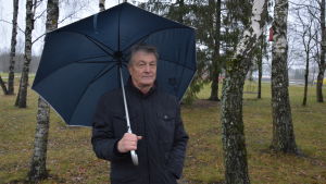 Sven Engblom har funderat på att ympa in mistel i den egna trädgården. Äldre man står med paraply bland träden.
