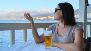 Bekvämlighetszonen? Den sträckte sig inte till Adriatiska havet, så jag struntade i den. Kvinna sitter på uteservering vid blått hav med öl framför sig