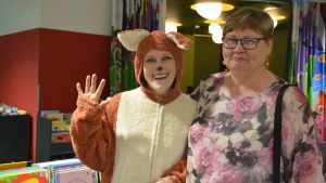 Biblioteksräven tillsammans med Ritva Nurminoro. En person utklädd till räv och en kvinna.