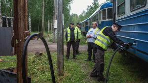 Dieselmoottorivaunut, eli lättähatut, tankataan hyvissä ajoin ennen museoajoa. Neljä henkilöä keltaisissa liiveissä, yksi heistä pitää dieselletkua, jonka pää on kiinni sinisessä junavaunussa.