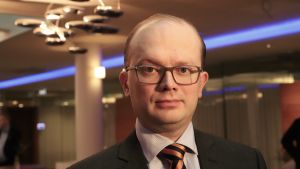 Inbromsningen är inte dramatisk, men den är klar, säger EK:s chefsekonom Penna Urrila. En kostymklädd man i glasögon ser in i kameran.