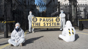 Demonstranter klädda i skyddsdräkter och masker krävde redan för flera dagar sedan hårdare tag mot coronaepidemin under en demonstration i London. Aktivister i skyddsdräkter och masker kräver hårdare tag mot coronaepidemin i en demosntration Strobritannien.