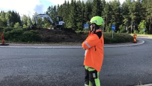 Mickos står och betraktar det som snart ska vara en förnyad version av rondellen vid Lovisas västra infart. Kvinna i reflexrock och hjälm står och tittar på en rondell som håller på att byggas om.