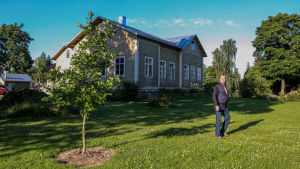 Karaktärsbyggnaden på Särklax gård är från 1867. En man står på en gräsmatta framför ett vitt gammalt trähus.