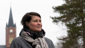 Lilian Järvinen vill se fler turister i Lovisa. En kvinna iklädd rock och halsduk står utomhus, i bakgrunden Lovisa kyrka.