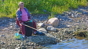 Yvonne Eriksson har vunnit flera metetävlingar. Kvinna sitter och fiskar på stranden.