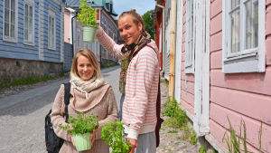 Kaisa Pekkala och Riku Kantola har just köpt färska örter. Man och kvinna står på en kullerstensgata med nyinköpta örter.