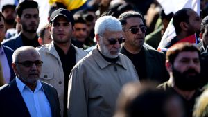 Abu Mahdi al-Muhandis ( i mitten) var biträdande kommendör för de shiamuslimska milisgruppernas takorganisation Hashed al-Shaabi. En klunga människor i en folksamling. I mitten en äldre man med grått hår, grått skägg, solglasögon och en beige jacka.