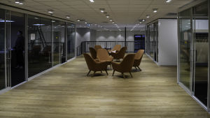 Sittgrupper med rymd. Bakom glasdörrarna finns mötesrum. Stolgrupper utanför möstesrum och kontorslandskap