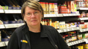 Köpman Monica Brunberg på Lantis i Ingå berättar att hon har haft jobbtelefonen med sig också när affären har stängt. En kvinna med glasögon, kort hår, klädd i svart fleecejacka. Hon står inne i en butik. Bakom hylla med kryddor och salladsdressingar och majonnäser.