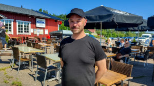 Joonas Seppelin hoppas att instrumenten ska hållas i händerna trots hettan. En man i svart t-skjorta står på en uteservering.