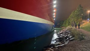 Grace låg helt intill stranden innan bogseringen. Viking Grace som kört på grund nära Mariehamn. Man ser ur nära stranden färjan är. Vid strandpromenaden går tre personer.