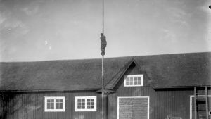 En man har klättrat upp i en flaggstång. Bilden är tagen 1931 i Närpes, Näsby.